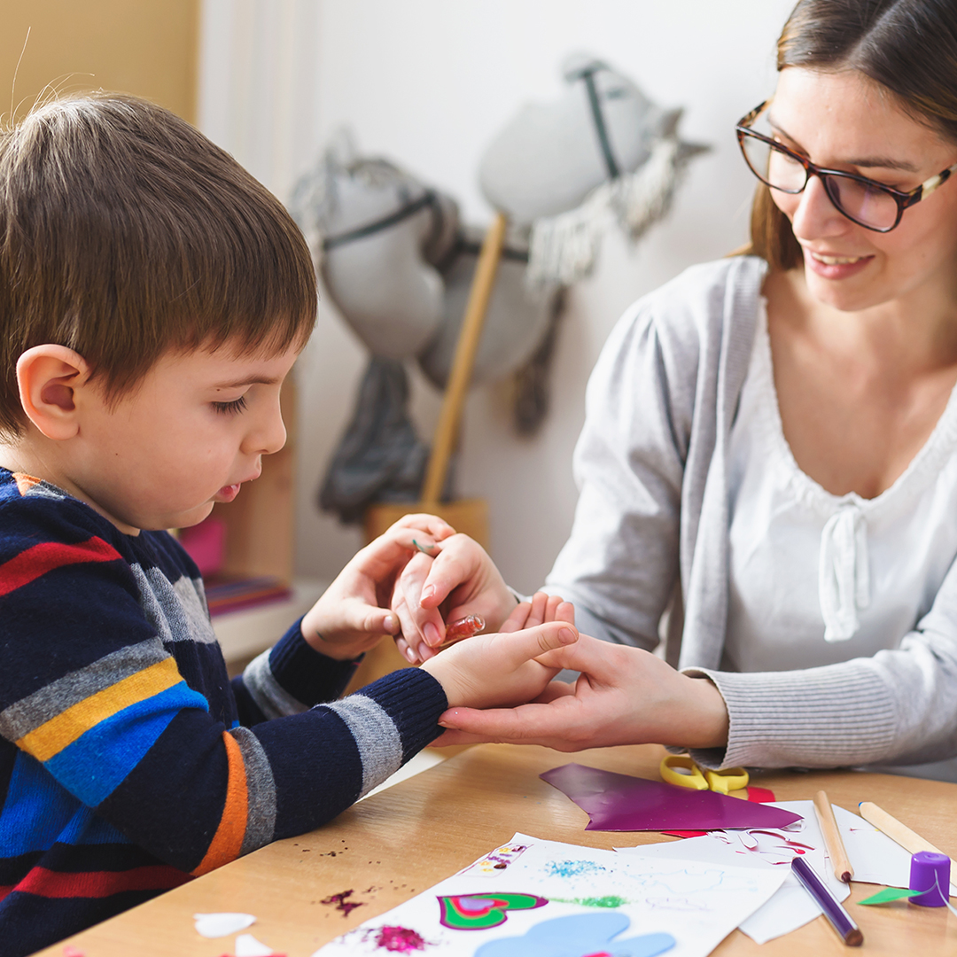 Image of a young boy painting with a teacher