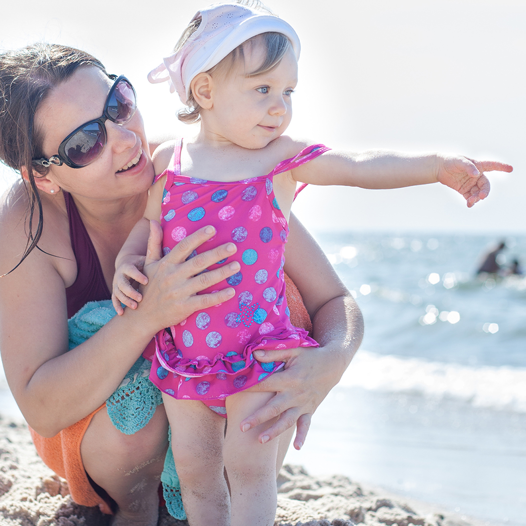 Image of a little girl on the beach with an adult